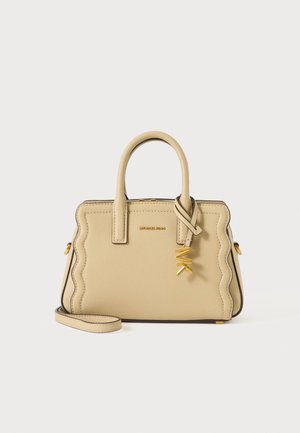 Beige læderhåndtaske med bølgede kanter, top håndtag, gyldent "MK" vedhæng og aftagelig skulderrem på ensfarvet baggrund.