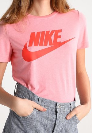 Camiseta de algodón de manga corta en color rosa, con un gran logo de Nike en rojo. La camiseta tiene un cuello redondo y un corte relajado.