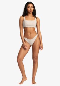 Striped bikini set in cream and brown. Includes a square-neck top with wide straps and high-rise bottom with a minimal coverage design.