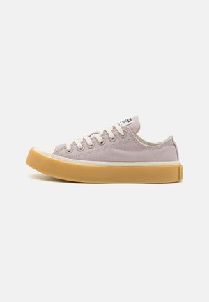 Light lavender canvas sneaker with a rubber toe cap and a yellow outsole. Features white laces and a logo tag on the tongue.