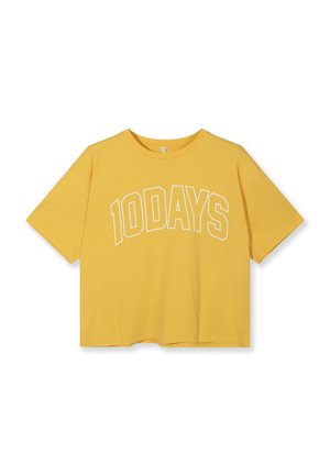 T-shirt jaune à manches courtes avec col rond et texte "10DAYS" en contour blanc, en arc de cercle sur la poitrine, sur fond blanc uni.