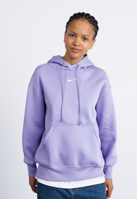 Fleece roxo da Nike com um bolso frontal, feito de material suave. Apresenta cordões ajustáveis e um pequeno logótipo branco no peito.