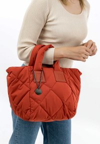 Borsa tote rossa imbottita con doppi manici, tessuto texturizzato, dettagli in pelle e una piccola catena decorativa con un'etichetta.