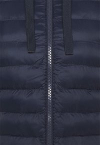 Gilet imbottito blu navy con trapuntatura orizzontale, chiusura frontale con zip e due linguette in tessuto. Texture liscia e lucida, design leggero, stile casual.