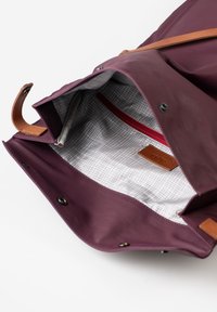 Borsa bordeaux con dettagli in pelle; l'interno presenta una fodera a motivo a griglia e una tasca con zip rossa. Chiusura a scatto magnetico nella parte superiore.