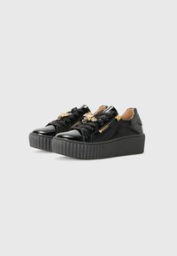Sneakers platform in vernice nera con suole in gomma testurizzata, chiusura con lacci, dettagli in metallo dorato e cerniere laterali.