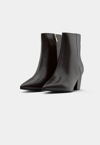 Botine negre până la gleznă cu un finisaj din piele netedă, vârf ascuțit și un toc mic pătrat. Dispune de un fermoar lateral și un design minimalist.