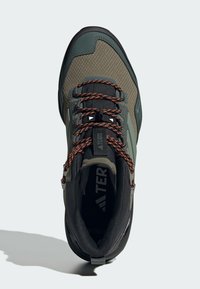 Buty turystyczne z szaro-zieloną siateczką, czarnymi akcentami, pomarańczowymi sznurówkami, wzmocnionym noskiem i teksturowaną gumową podeszwą.