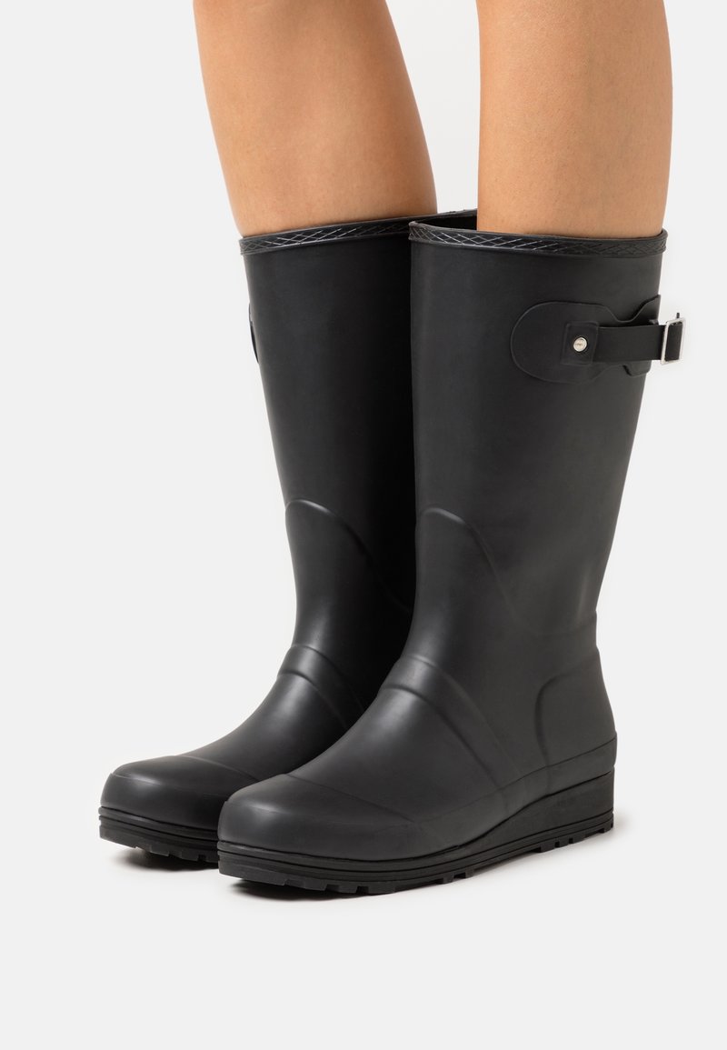Bottes de pluie en caoutchouc noir avec un bout arrondi, des accents texturés sur les côtés et un détail de boucle sur le haut. Semelle texturée pour une meilleure adhérence.
