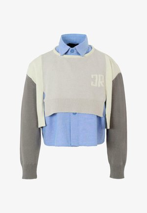 Warstwowy krótki sweter z jasnoszarym dzianinowym topem, beżowymi akcentami i niebieską koszulą z kołnierzykiem pod spodem, z ozdobnymi guzikami.