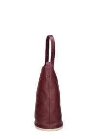 Bordeauxrood lederen shoppers met een gestructureerde afwerking, een enkele handgreep en een afgeronde bodem. Geen zichtbare hardwaredetails.