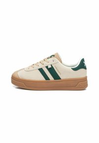 Zapatillas de ante beige con rayas verdes, suela de goma y cuello acolchado. Presenta un logo cerca de los cordones y acentos texturizados en la suela.