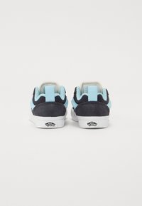 Dunkelblaue und hellblaue Wildledersneaker mit weißen Gummisohlen. Eigenschaften umfassen einen gepolsterten Schaft und einen Logo-Detail-Backtab.
