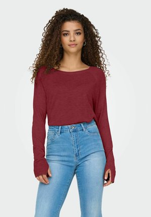 Haut à manches longues bordeaux avec un col bateau, associé à un jean en denim bleu clair taille haute. Texture douce et coupe décontractée.