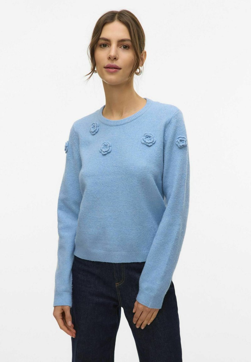 Maglione azzurro chiaro realizzato in un tessuto morbido, con applicazioni di fiori in rilievo sulla parte anteriore, col collo rotondo e orlo a coste.