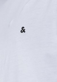 White short-sleeve t-shirt made of soft fabric, featuring a small black embroidered logo on the left chest area.