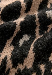 Strickstoff mit einem Leopardenmuster-Design, das schwarze Flecken auf einem hellbeigen Hintergrund zeigt. Weiche Textur mit sichtbaren Fasern und Stichen.