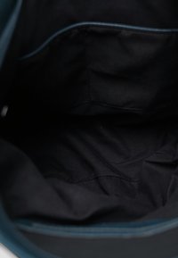 Blauwe tasinterieur met een soepele textuur, voorzien van een zwarte stoffen voering en zichtbare binnenvakken voor organisatie.