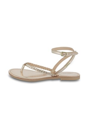 Sandal flat con cinturini intrecciati dorati, una sottile cinghia alla caviglia con fibbia, suola in pelle beige e una texture liscia.