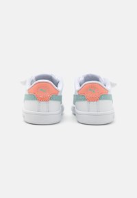 Baskets blanches avec des accents bleu clair et corail. Elles présentent une tige en textile doux et une semelle en caoutchouc lisse. Logo Puma à l'arrière.