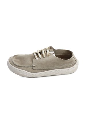 Zapato casual tipo slip-on con parte superior de ante beige, cordones blancos y suela de goma blanca, mostrado de lado sobre un fondo blanco.