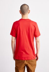 Red cotton t-shirt with a crew neckline and short sleeves, featuring a plain design and visible stitching details on the hem.
