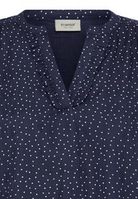 Blouse bleu marine à pois blancs, col en V à volants et tissu texturé, avec étiquette de marque "fransa".