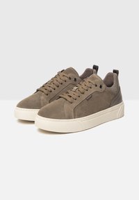 Sneaker in suede di un colore marrone tenue con suole in gomma crema, dotate di lacci tondi e un logo sottile sul lato.