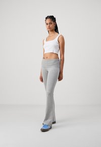Hallide ülaservaga hallid lai aluspüksid, millele on sobitatud lühike valge tank top. Mudel kannab siniseid ja pruune sneakers'e. Sile kangamaterjal.