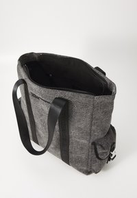 Siva platnena torba s crnim trakama, zatvaranjem na zip, unutarnjim džepom i vanjskim detaljima. Tekstuirana površina, pravokutni oblik.