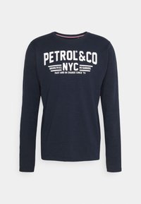 Námořnická modrá košile s dlouhým rukávem a bílým textem "PETROL & CO NYC" a dalším menším textem na hrudi, zobrazená na bílém pozadí.