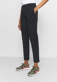 Svarta slim-fit byxor i en slät kvalitet, med sidfickor och rak skärning, kombinerade med grå och rosa träningsskor.