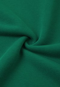 Zielona bawełniana tkanina o gładkiej fakturze, z drobnym splotem, który nadaje miękki wygląd i lekki połysk.