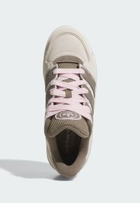 Beige athletic shoe with pink laces, suede and mesh materials, featuring brown accents and a logo on the tongue, rounded toe design.