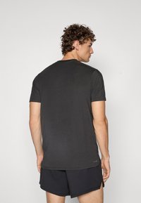 Dunkelgraues, kurzärmliges T-Shirt mit rundem Ausschnitt. Weicher Stoff, lockere Passform und glatte Textur, mit einem dezenten Markenakzent nahe dem Saum.
