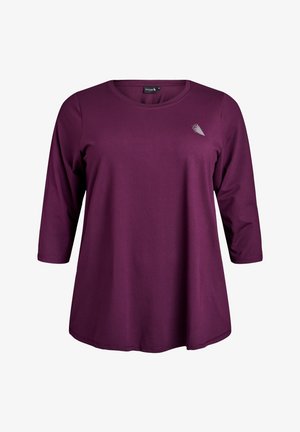 Langærmet trøje med rund hals i mørk lilla strækstof. Har en lille metallisk detalje på øverste venstre side. Glat tekstur.