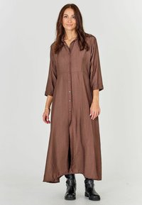 Brown, button-up maxi dress with three-quarter sleeves and textured fabric. The dress features a high-low hem and falls to mid-calf.