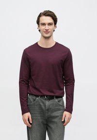 Pikad varrukad, ümara kaelusega särgipluus sügavbordoopunases puuvillas, kombineeritud hallide teksapükstega, millel on tavaline lõige ja klassikaline viie taskuga disain.