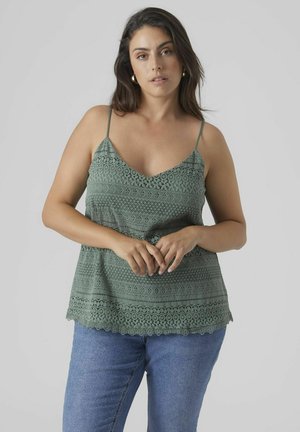 Green lace tank top with adjustable spaghetti straps, intricate patterns, scalloped hem, paired with blue jeans. Cotton blend material.