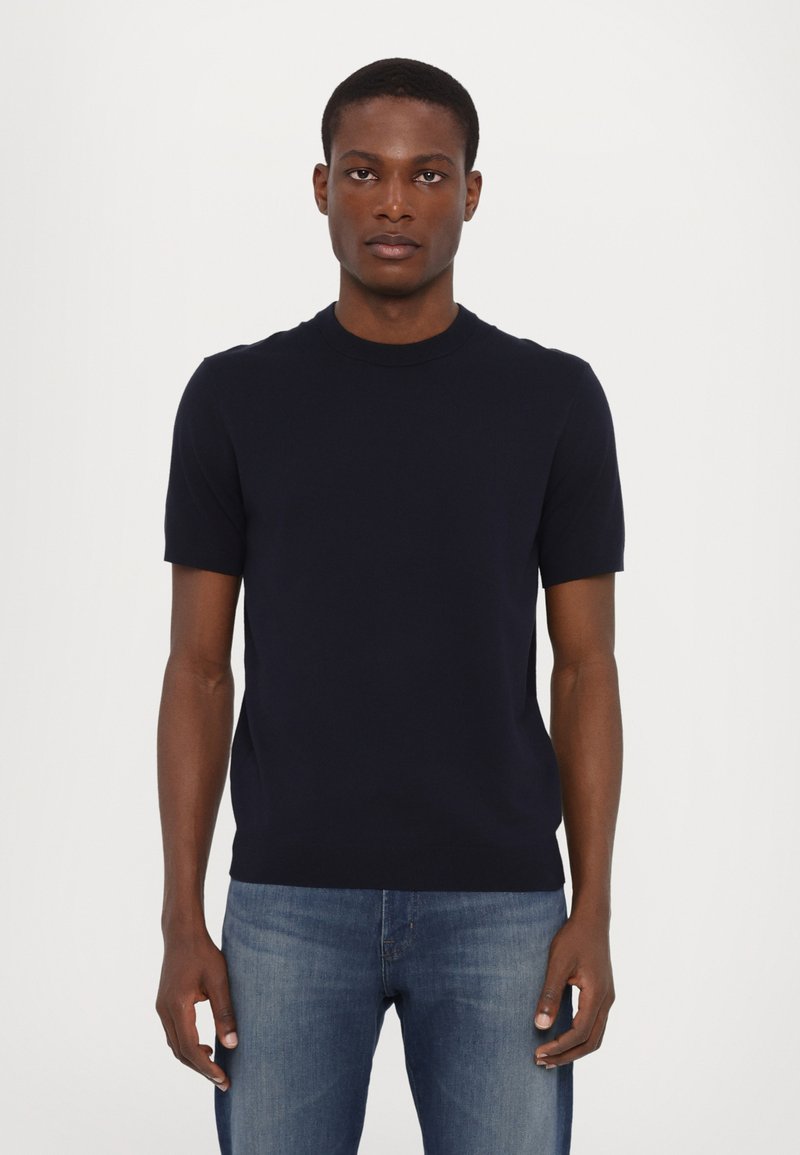 Navy korte mouwen crewneck gebreide trui van zacht materiaal, met een aansluitend ontwerp en een gladde textuur, gecombineerd met lichtblauwe spijkerbroek.