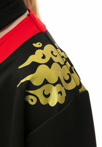 Schwarze Stoffjacke mit einem auffälligen roten Kragen und intricaten goldenen Wolkenmustern. Das Design umfasst glatte, glänzende Texturen und Details.