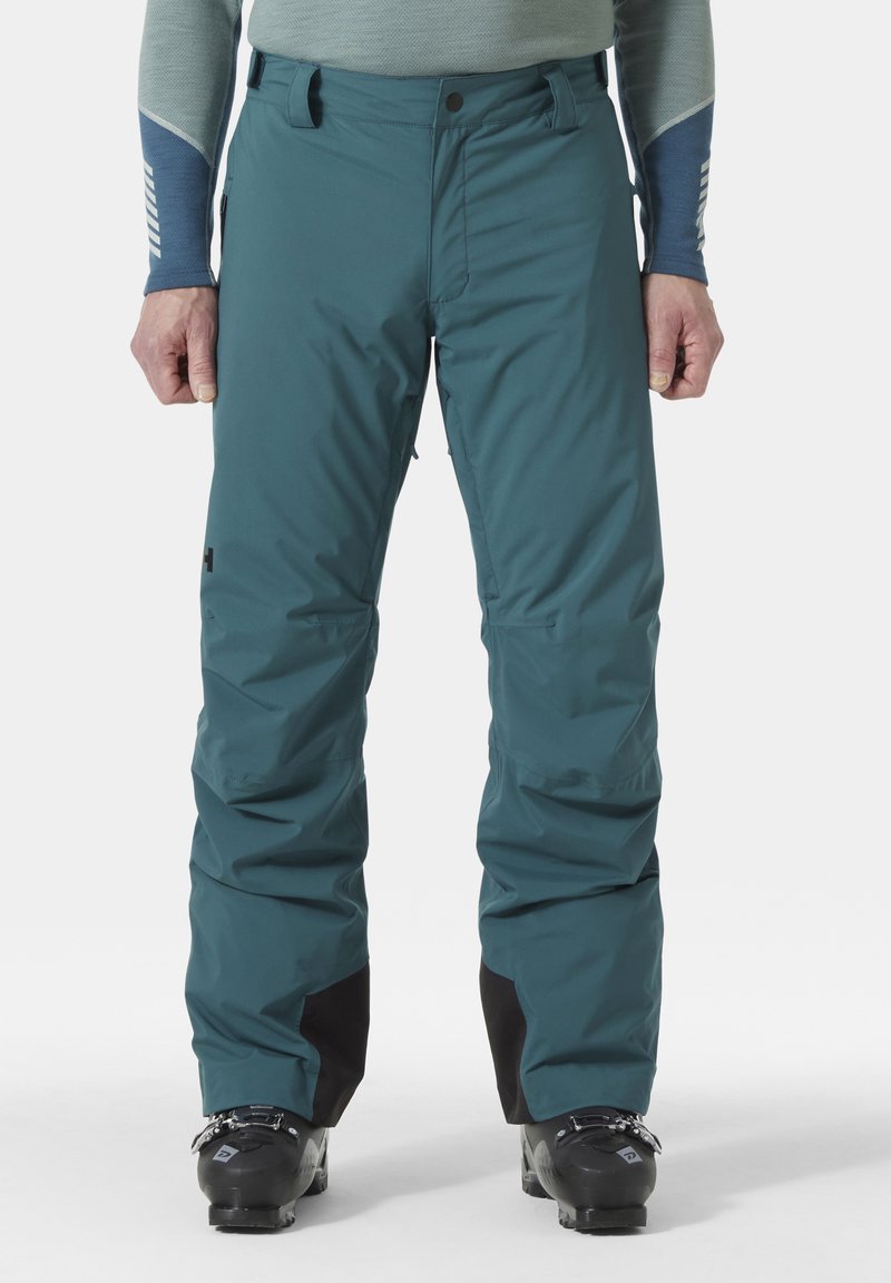 Teal-huuru ski-housut, joissa on sileä, vedenpitävä materiaali. Ominaisuuksiin kuuluvat vahvistetut mustat yksityiskohdat lahkeissa ja sivuissa olevat vetoketjutaskut. Slim fit -malli.