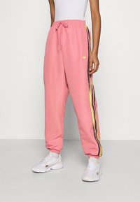 Rosa bomullsjoggers med elastiskt midjeband, prydda med svarta och neon-gula sidostreck samt en liten logotyp på framsidan.