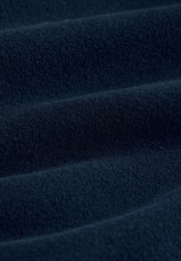 Námořnická fleecová látka s měkkým, texturovaným povrchem, s hladkými, plynulými záhyby a konzistentní barvou po celém materiálu.