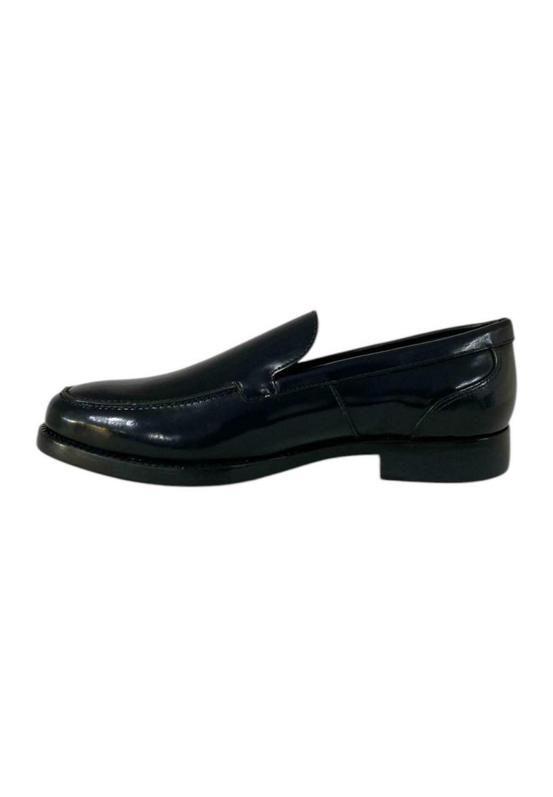 Scarpa nera in pelle senza lacci con finitura liscia, caratterizzata da una punta arrotondata, cuciture minime e un tacco basso e piatto.