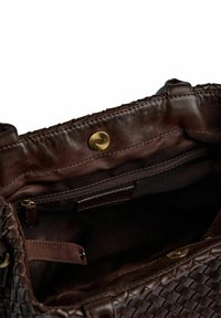 Borsa a mano in pelle intrecciata marrone scuro con scomparto principale aperto che mostra l'interno in tessuto, tasca con zip e chiusura con bottone a calamita.