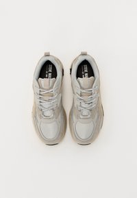 Szare sneakersy z materiałów siateczkowych i zamszowych, z okrągłym noskiem, teksturowanymi akcentami i szarymi oraz białymi paskami do sznurowania. Czarna wewnętrzna marka.