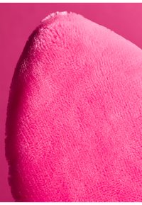 Vloeiende, pluchen kussen in levendig roze, met een ronde rand en zachte textuur. De achtergrond is een effen roze kleur.