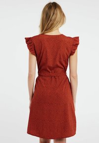 Röd kortärmad klänning med ett helsvart prickmönster, volangärmar och en midjeband, som har en avslappnad passform och en mjuk textur.