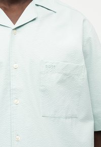 Ανοιχτό πράσινο πουκάμισο με κοντά μανίκια και υφή, με κουμπιά και αριστερή τσέπη στο στήθος κεντημένη με το λογότυπο "BOSS".